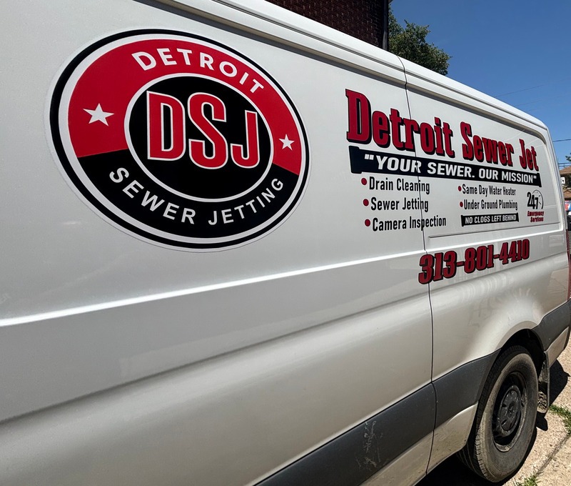 Close-up of a Detroit Sewer Jetting service van displaying the company logo and a list of plumbing services including underground plumbing.