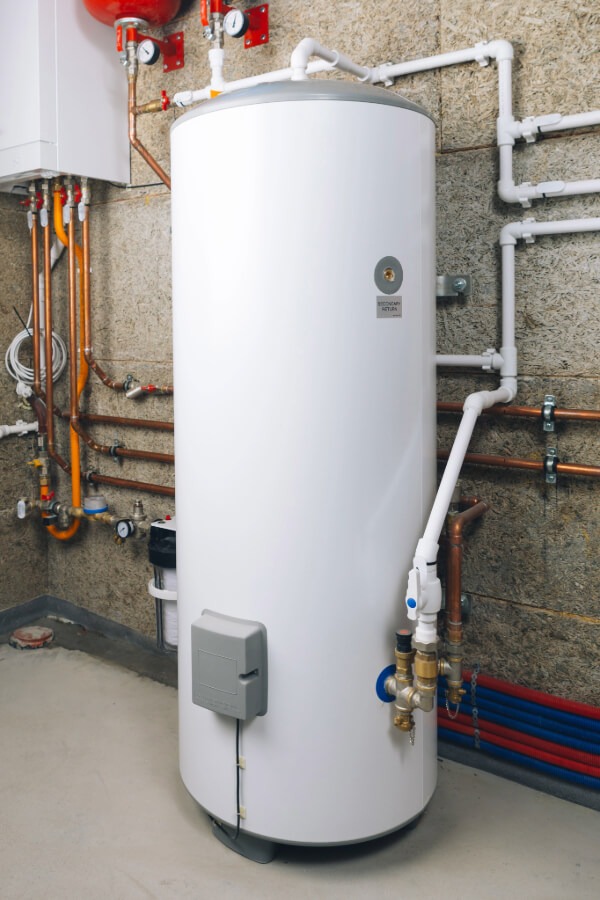 A clean, modern white tank connected to a network of copper and PVC plumbing pipes, showcasing expert installation for residential water heaters.